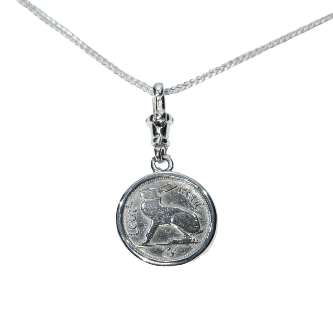 The Hare Silver Pendant by The Silver Rabbit features a sterling silver round charm with an engraved sitting rabbit and Arabic script, reminiscent of an Irish threepence coin, on a delicate chain.
