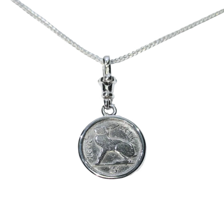 The Hare Silver Pendant by The Silver Rabbit features a sterling silver round charm with an engraved sitting rabbit and Arabic script, reminiscent of an Irish threepence coin, on a delicate chain.