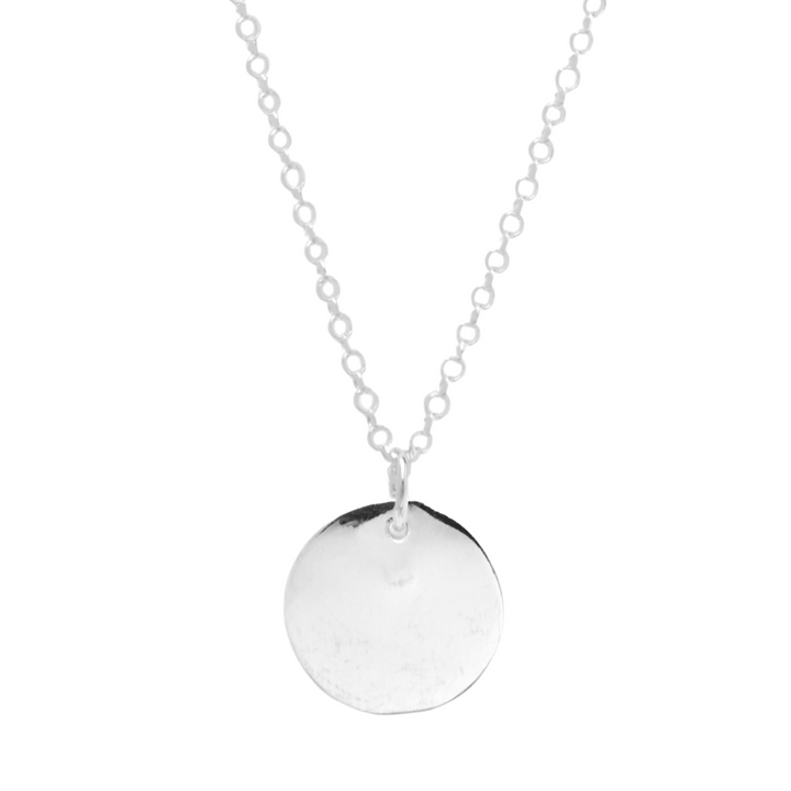 The Simple Disc Pendant by Personalised Charms is a delicate sterling silver necklace with a simple, round flat engraved pendant at the center.