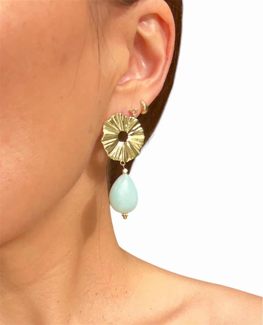 Close-up of a woman’s ear wearing Aria V Sky Amazonite Earrings, handmade in Ireland with a textured gold-plated brass circle and a teardrop-shaped amazonite stone, set against a plain white background.
