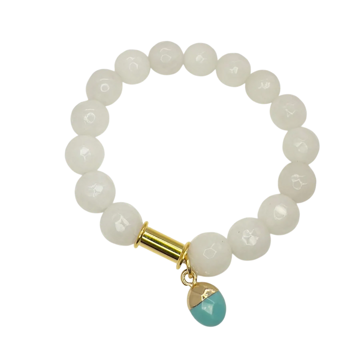 The Soulstone White Agate and Turquoise Bracelet by Aria V features glossy white agate beads, a gold accent, and a turquoise charm, all handmade in Dublin and elegantly displayed on a white background.