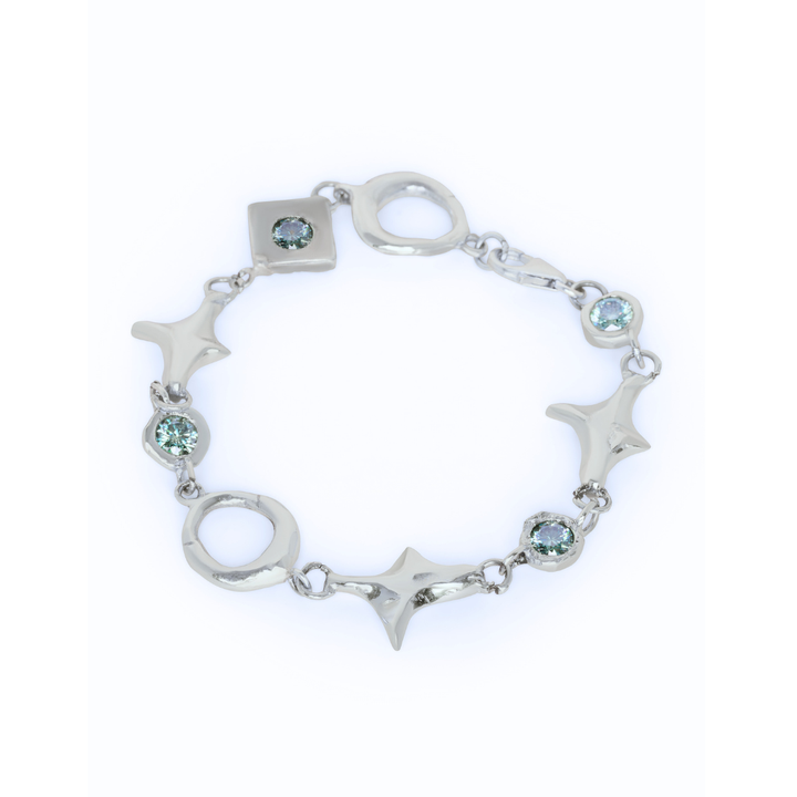 Introducing the Madeleine Blaine Spark Bracelet, showcased on a white background. This elegant silver bracelet features round, square, and star-shaped links adorned with delicate light blue gemstones. Its distinctive design celebrates unique connections and positive energy.