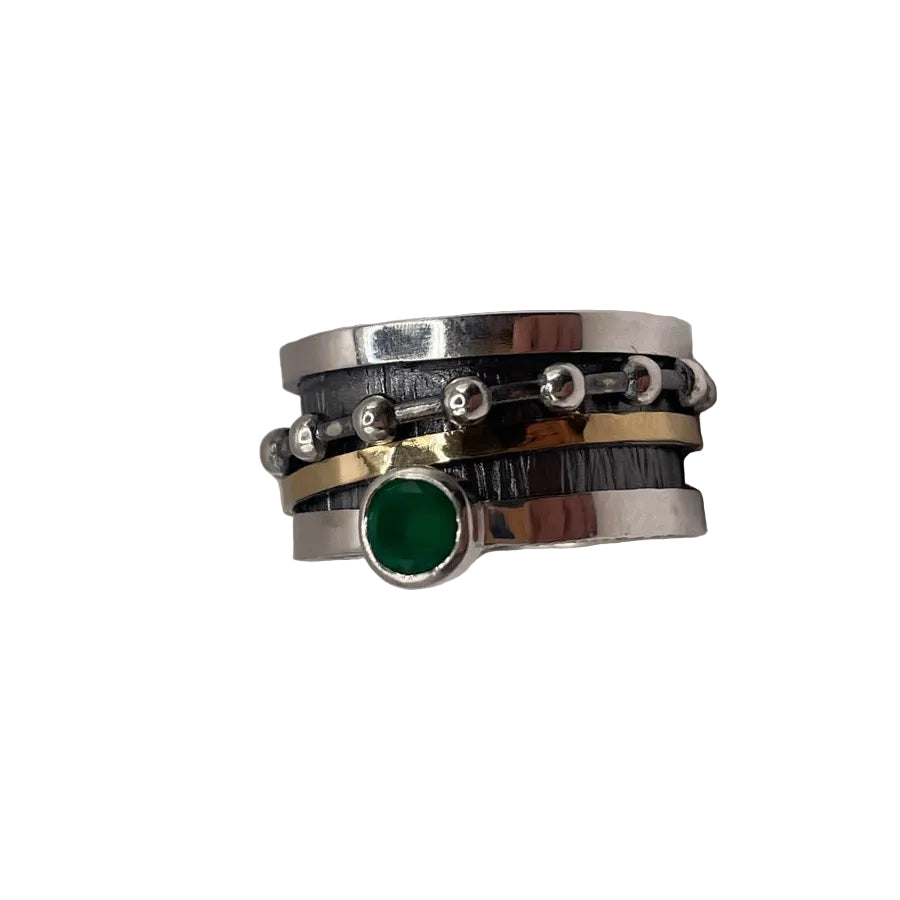 The K.And Spinning Ring Silver with Oxidisation, 18k Gold & Green CZ features layered sterling silver bands, a central green cubic zirconia, an 18k gold accent band, silver beads, and textured oxidised detailing.