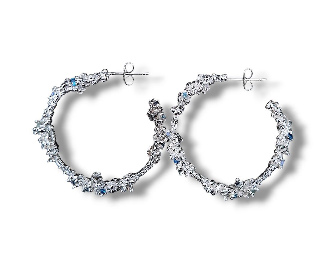 The Pale Raven Starborne Sterling Silver Hoop Earrings feature a textured, organic design with small lab grown crystals, shown against a white background with soft shadows.