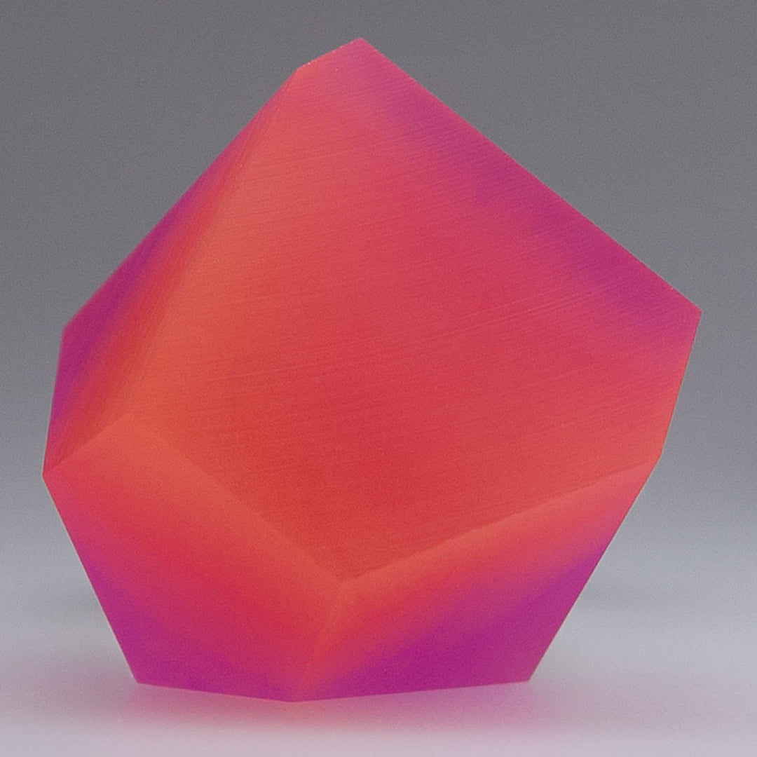 The Fruit Bijoux Ring Top VU Crystals Sunset Pink by Fruit Bijoux features smooth, faceted surfaces in vibrant Sunset Pink and purple hues, reminiscent of crystals, set against a simple gray background.