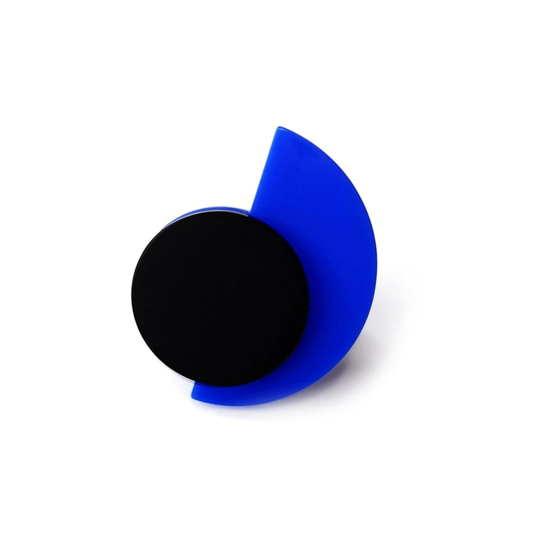 A geometric art piece, reminiscent of the Suzan Ring by Alex + Svet, features a solid black circle overlapping with a semi-translucent blue semicircle. The blue semicircle is positioned to the right, partially covering the black circle and creating a dynamic, minimalist composition.