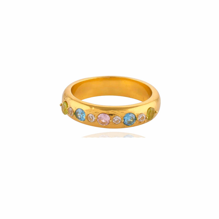 A Tasha Ring made from 22 carat gold, adorned with light blue, light pink, and clear gemstones arranged in a row along the top half. The gold band has a smooth and polished finish, reflecting light. The hypoallergenic jewelry piece is set against a plain white background.