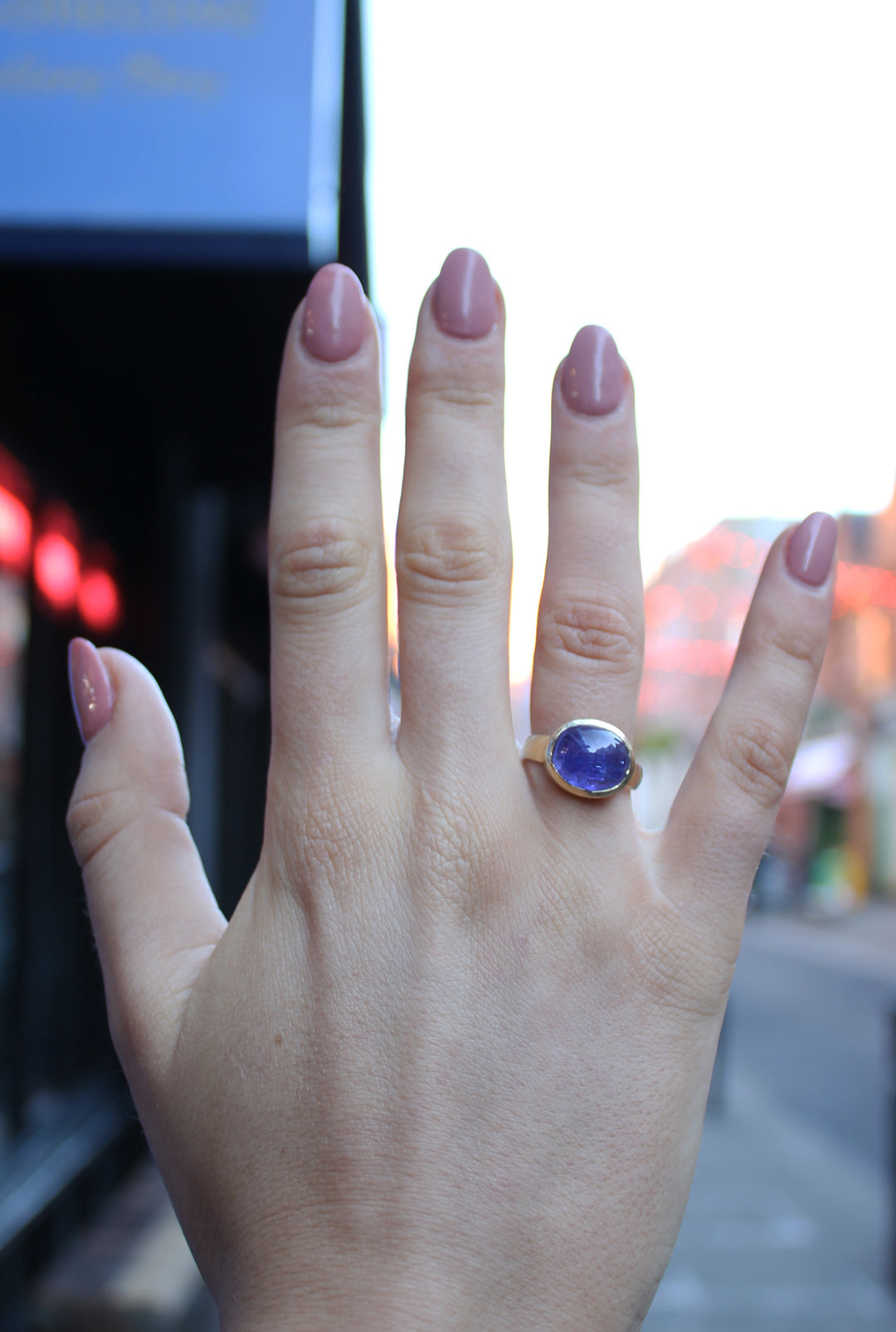 9ct Yellow gold ring with a large oval cabochon Tanzanite, which is a dark blue purple colour. The 9ct yellow gold band is D shaped with the widest at the back at 3mm. Shown here on a ring finger