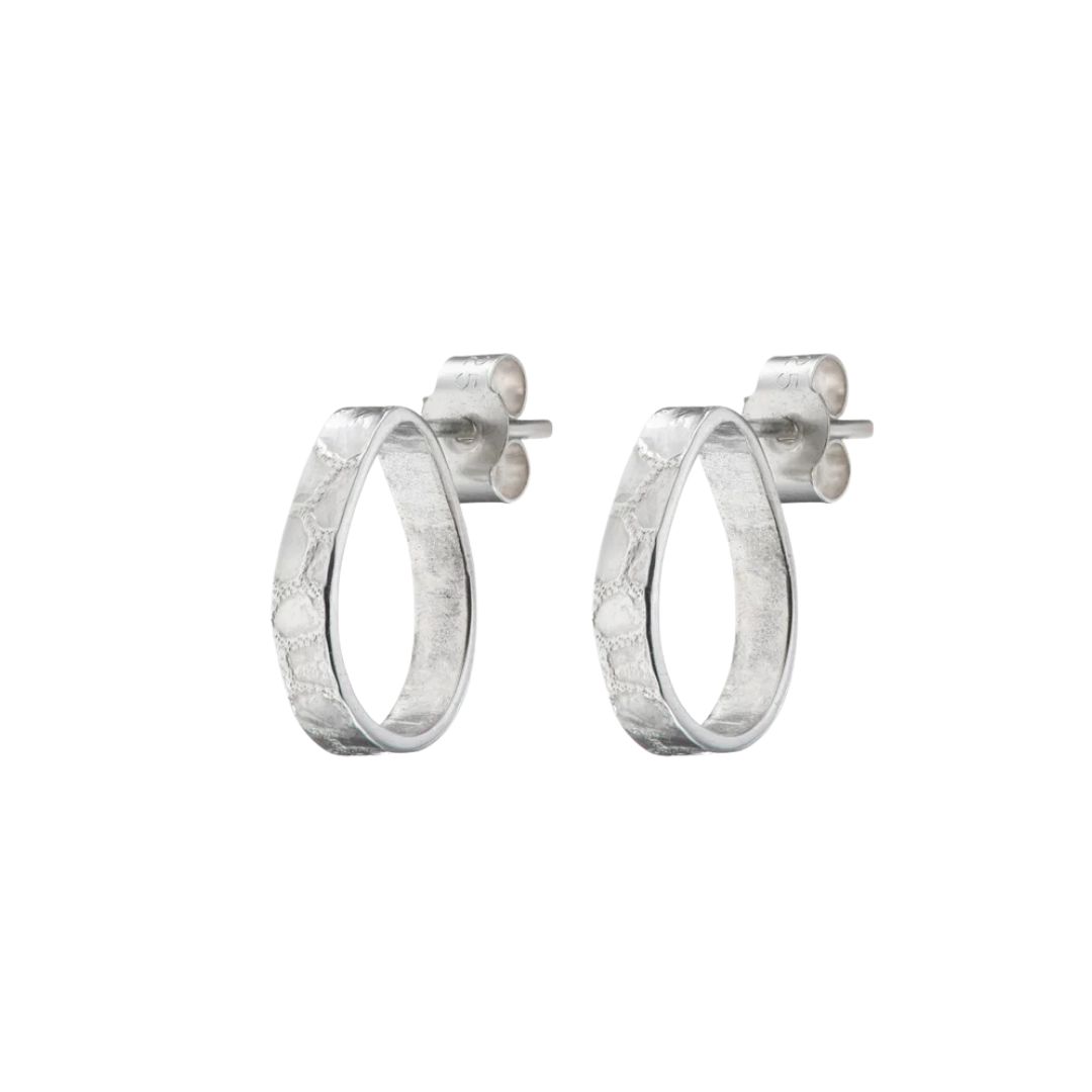 The Talún Studs by Lynsey de Burca are handmade sterling silver earrings with a hammered finish, featuring a modern minimalist design and secure butterfly backs.
