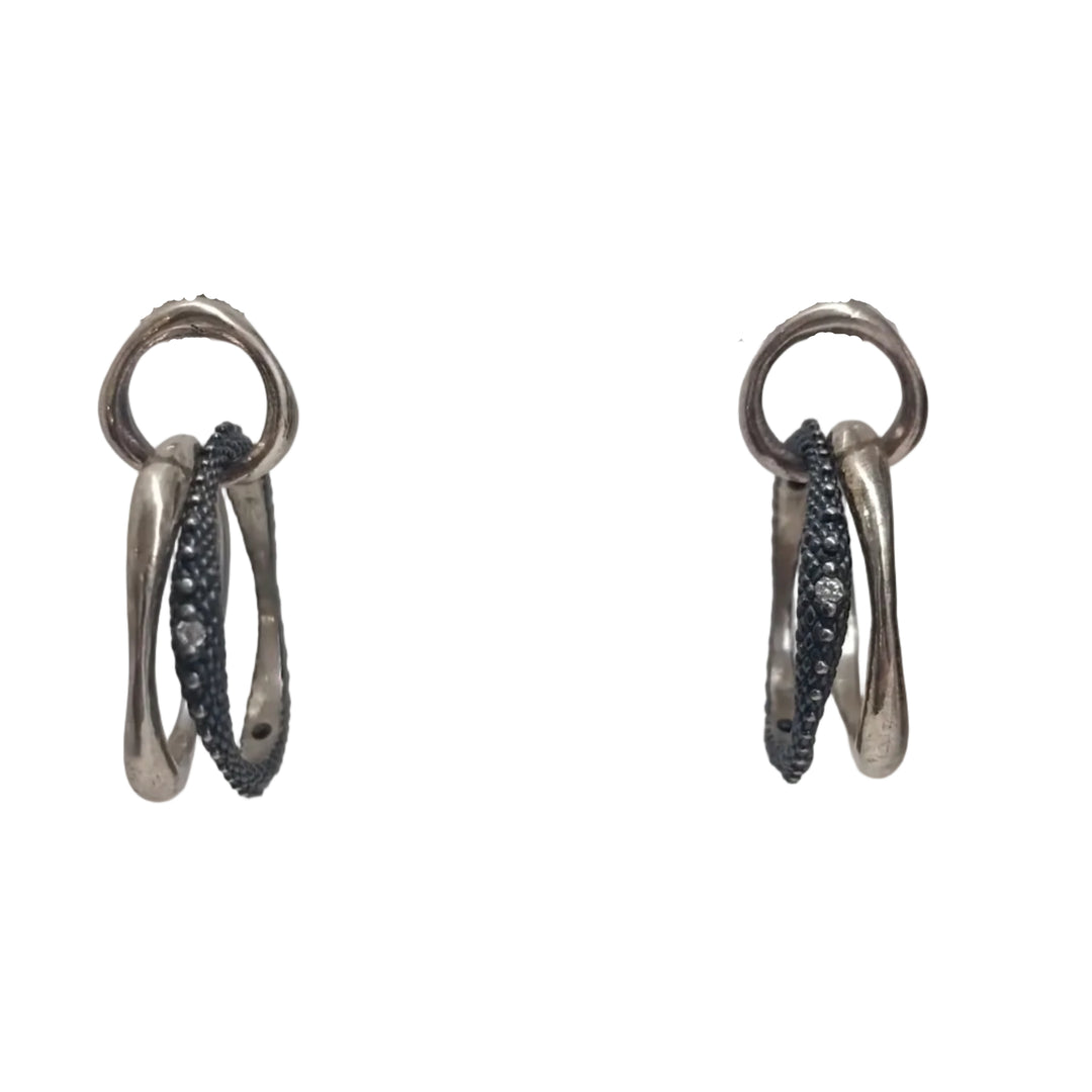 The K.And Textured & Oxidised Interlocking Circle Earrings with CZ feature two sterling silver loops—one smooth, one dark and CZ-encrusted—dangled stylishly against a white background.