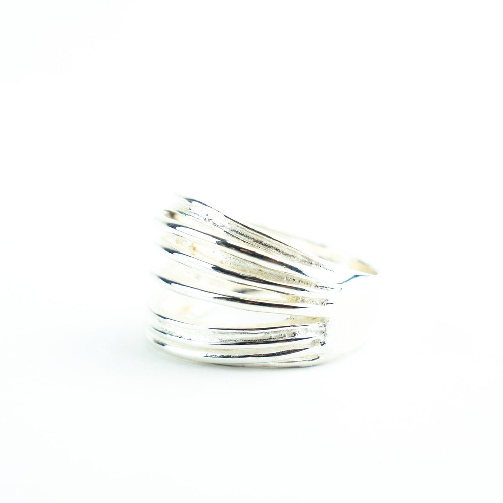 A Multi Ring Silver by Watermelon tropical featuring a layered, wave-like design with smooth yet irregular horizontal bands stacked on top of each other. The ring's polished surface reflects light, creating a luminous and elegant appearance against the plain white background.