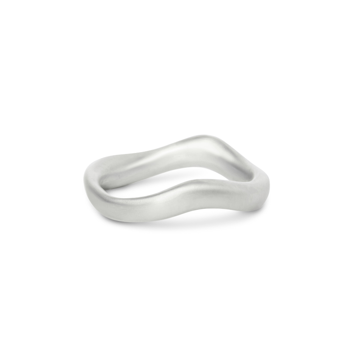 The Thorn Ring by Madeleine Sculptural Jewellery is a simple silver band featuring a smooth, organic wavy design, reminiscent of hand-carved artistry, showcased against a white background.