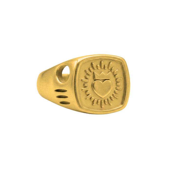 The Collective Dublin’s Keith Haring Inspired Claddagh Ring is a handmade piece featuring a square face with a heart, crown, and radiating lines. The band showcases a round hole plus three small oval cutouts on one side.