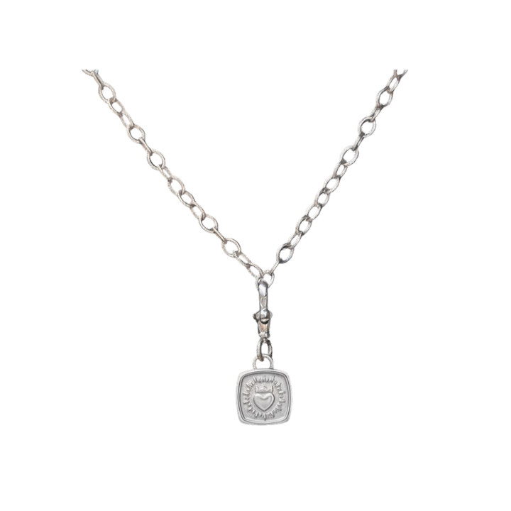 The Collective Dublin’s Keith Haring Inspired Claddagh Pendant with chunky chain features a silver necklace with an etched square pendant showcasing a sunburst design and a small heart at the center, subtly nodding to Keith Haring-inspired jewelry—elegantly presented against a white background.