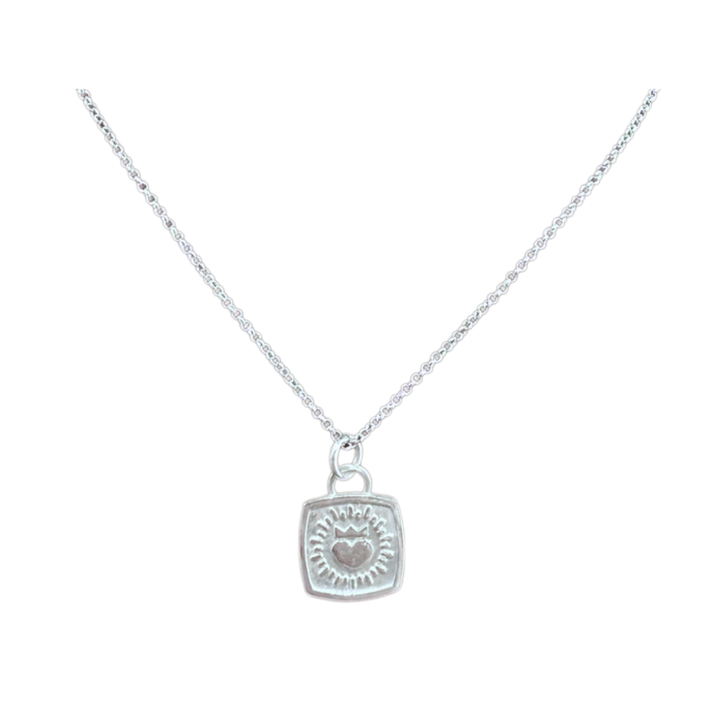 A Keith Haring Inspired Claddagh Pendant by The Collective Dublin, crafted in sterling silver with a square design featuring an engraved sunburst motif and a small central heart, reminiscent of classic Irish jewelry, displayed on a white background.