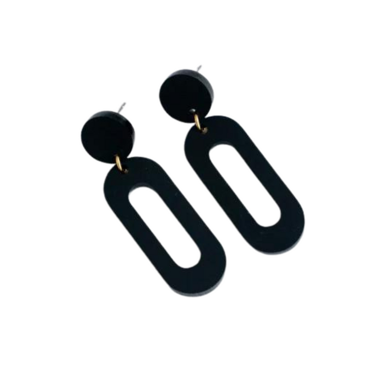 The Timeless 04 Oval Acrylic Earrings by Studio Nok Nok are a pair of black, geometric earrings featuring circular studs connected to elongated, oval-shaped loops with a cutout center, creating a minimalist and modern design. These perfect earrings are crafted from recycled materials for an eco-friendly touch.