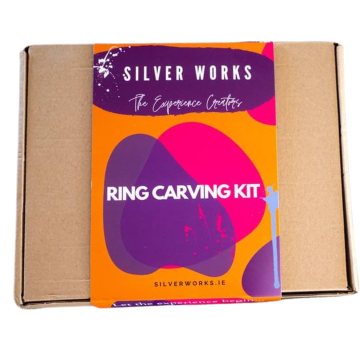 An image of a cardboard box with a bright and colorful label on top. The label reads "Silver Works - Ring Carving Kit." The background features an orange and purple abstract design, highlighting the expertise of jewellery artisans. Visit "silverworks.ie" for your virtual experience.