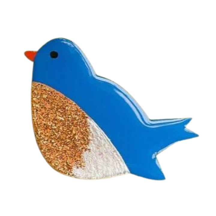 A colorful art depiction of a handpainted wooden Bluebird Pin Brooch by Naoi. The bird's head and tail are painted bright blue, its beak is orange, and it features a sand-textured body section with a speckled and lightly glittery appearance. The bird has one small black eye.