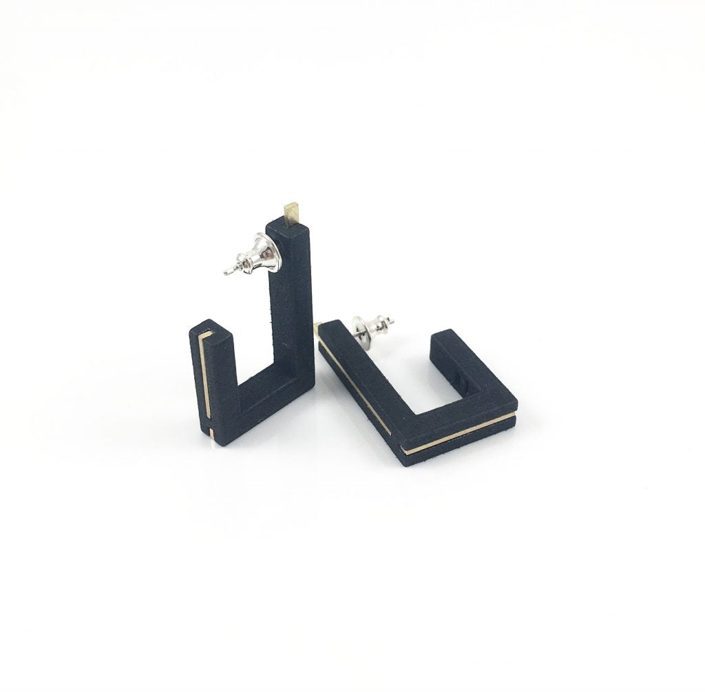 A pair of black, square-shaped 3D printed Vibe Brutalist Earrings by Elsiem with silver posts and backs displayed against a white background. The earrings have a modern, minimalist design with a geometric form and subtle gold accents along the edges, reminiscent of Brutalist Architecture.