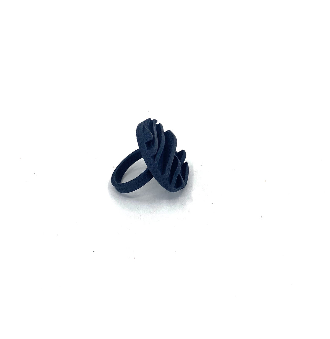 A black, dome-shaped, 3D printed ring with a unique wavy design on the top is set against a white background. The SLS Nylon construction and matt black dye enhance the modern and abstract design of the Vibe Wave Circle Fascia Ring by Elsiem, adding a sculptural element to the piece.