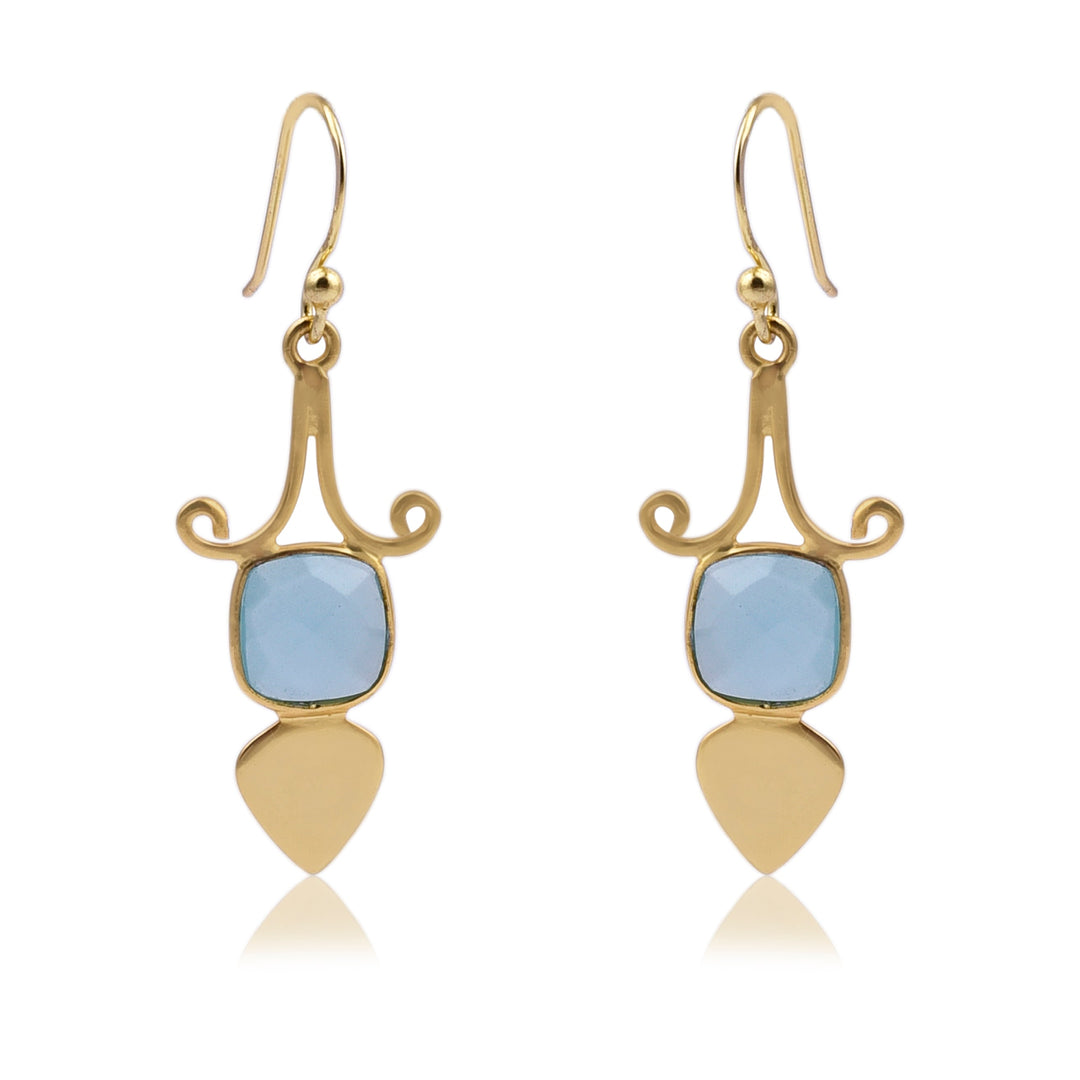 A pair of elegant Gold Shield Aqua Chalcedony Earrings by Watermelon Tropical featuring a curved design at the top, with a square blue gemstone in the center, and ending with a teardrop-shaped gold piece at the bottom. These exquisite pieces of handmade jewellery have hook closures.