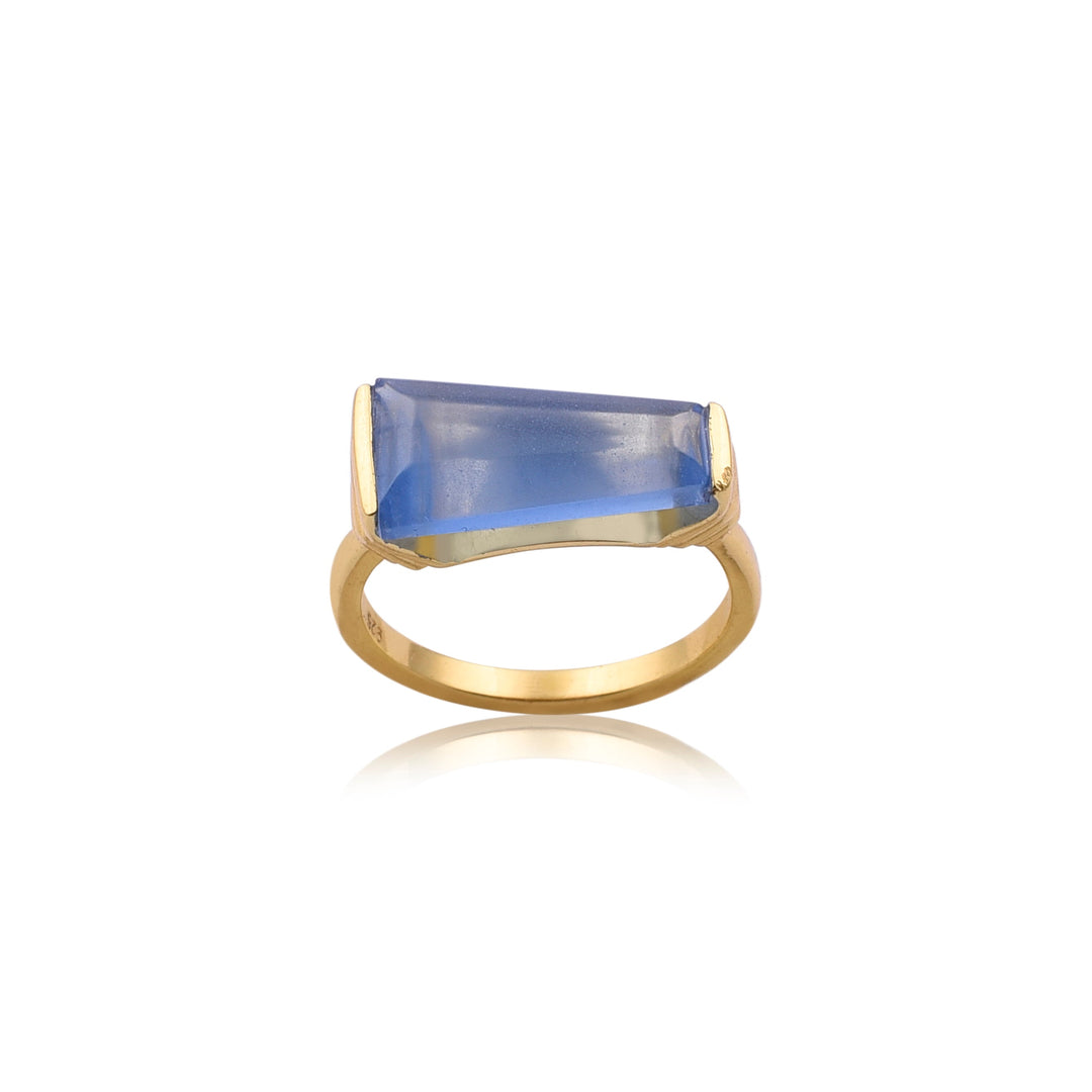 A Blue Quartz Gold Ring by Watermelon Tropical featuring a rectangular, faceted blue quartz gemstone. The stone is set horizontally and secured by two end prongs. The ring is simple with a smooth, polished band, showcasing the beauty of handmade jewellery.