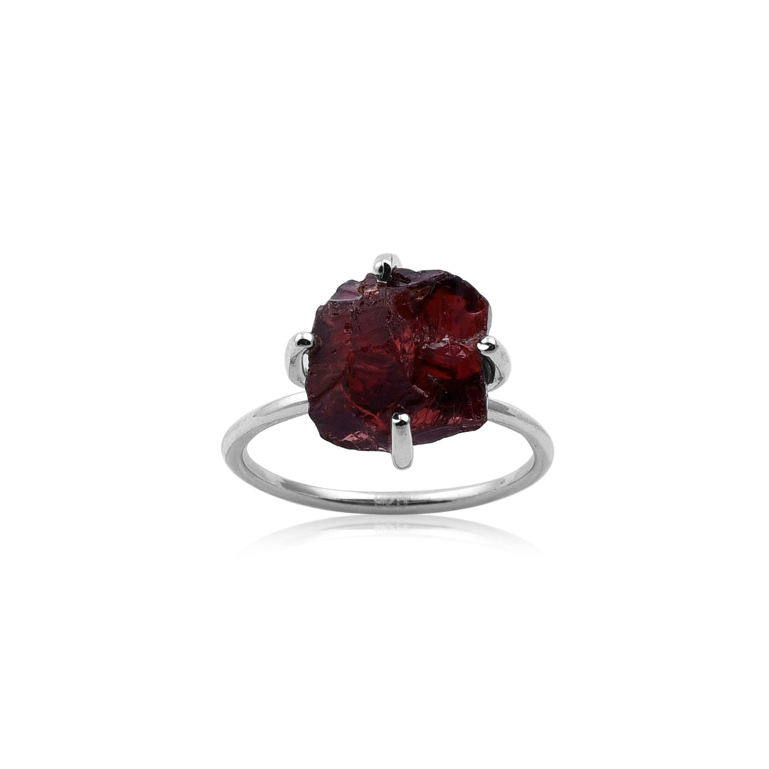 A Watermelon Tropical Rough Garnet Silver Claw Ring featuring a large, rough-cut deep red Rough Garnet stone held by four prongs. The stone has an uneven, natural texture, and the ring's band is smooth and polished. The white background highlights the intricate design of this handmade jewellery piece.