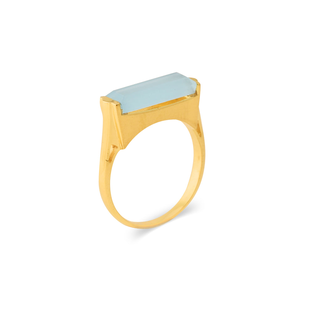 Gold plated ring with long, rectangular pale blue stone. The side of the ring is photographed here against a white background.