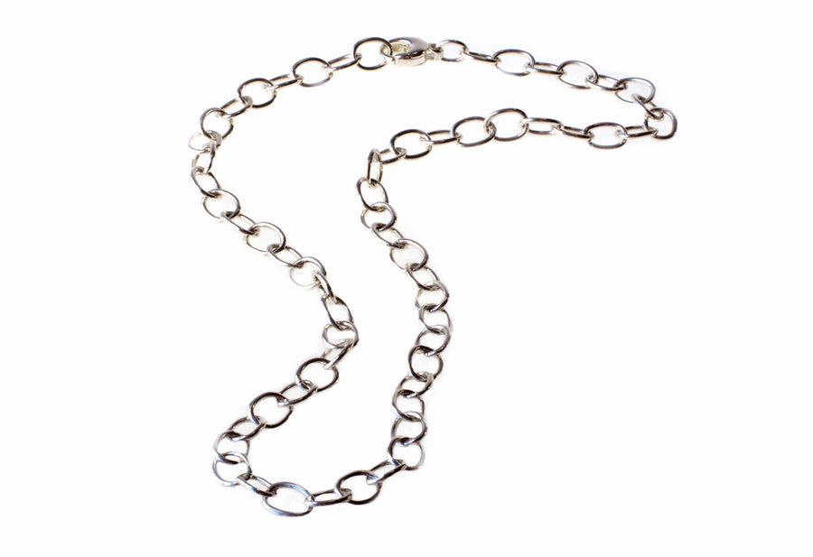 A Detlef Menard Wide Anchor Chain with large, rounded links crafted from recycled sterling silver is arranged in an asymmetrical, slightly curved fashion against a white background. The uniformly spaced and interconnected links give the handcrafted chain a simple yet elegant appearance.