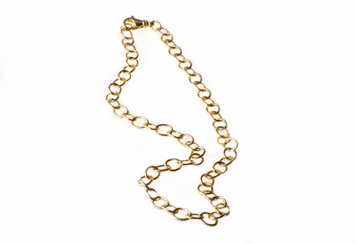 A handcrafted Wide Anchor Chain by Detlef Menard is laid out on a white background. The chain consists of large, oval-shaped links connected in a continuous pattern, giving a shiny and elegant appearance.