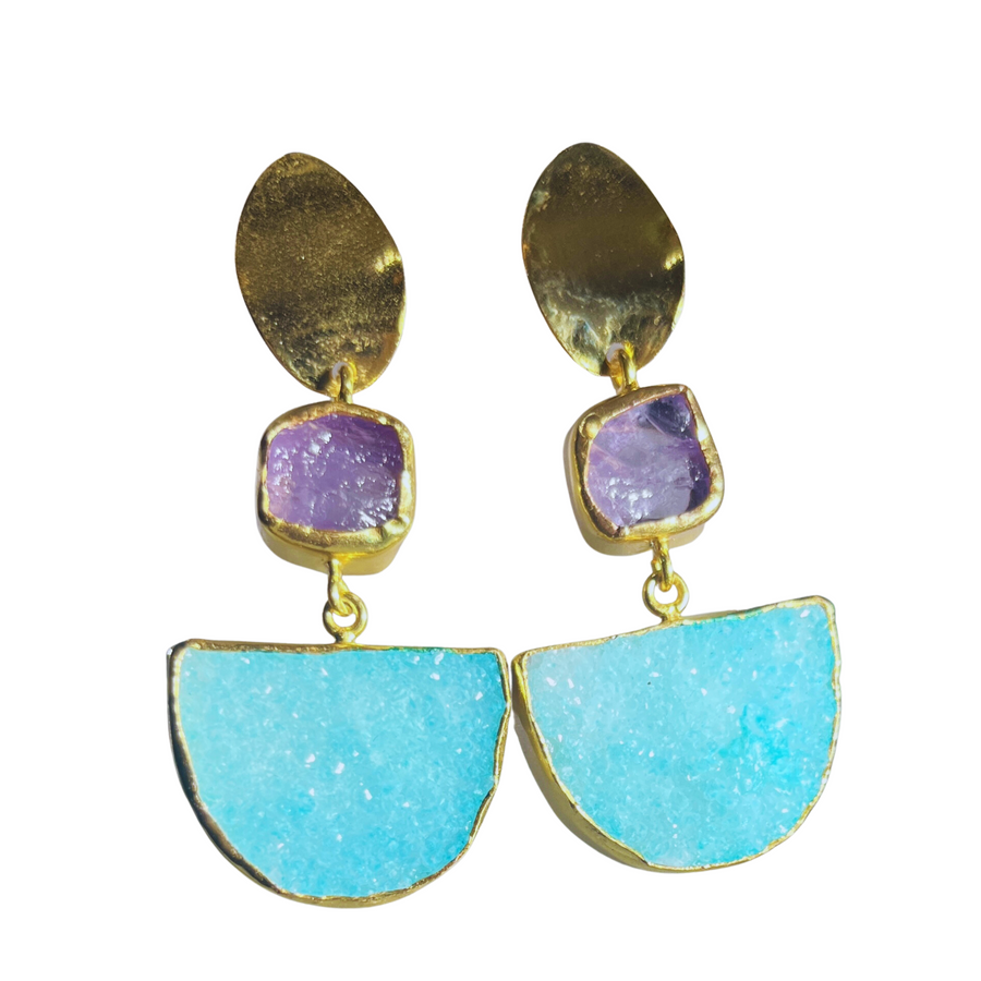 A pair of gold-plated Amazonia Earrings In Amethyst & Aqua Druzy by Watermelon Tropical featuring large turquoise semi-circular stones at the bottom, small square purple stones in the middle, and gold-toned oval shapes at the top. The stones are faceted and the earrings have a vibrant, eclectic design.