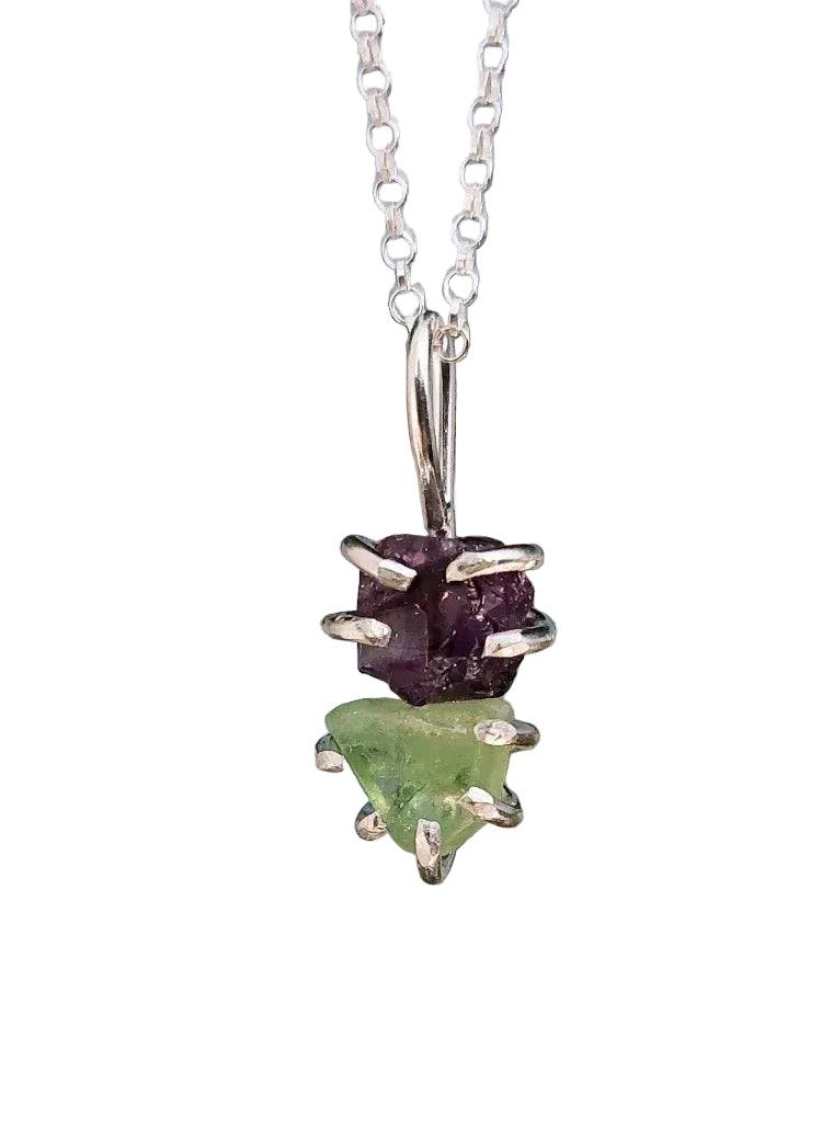 The Raw Amethyst & Peridot Elements Pendant by Caroline Stokesberry-lee features two rough, uncut gemstones—amethyst and peridot—stacked vertically in silver prongs, ideal for lovers of spiritual jewelry.