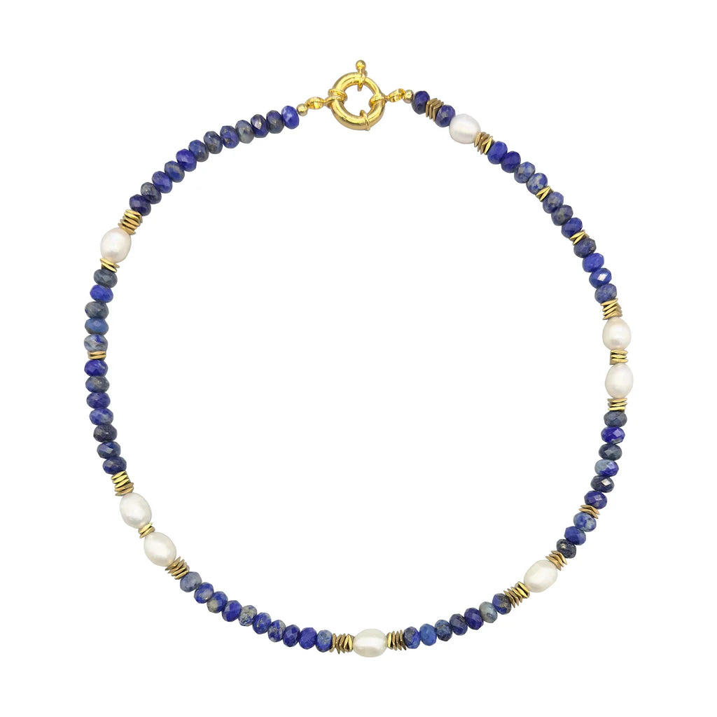 The Ariel Necklace by Aria V is a handmade choker with alternating deep blue lapis lazuli beads, white pearls, and gold spacers, finished with a gold round clasp—a unique piece of Dublin jewelry.