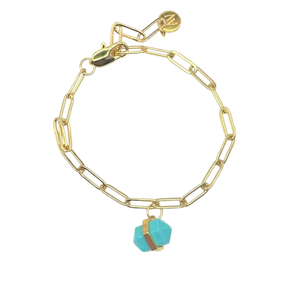 The Aria V Ayin Bracelet features elongated gold links, a blue geometric gemstone wrapped in a thin gold band, and a round gold tag by the clasp—an elegant handmade piece that adds a unique touch to any outfit.