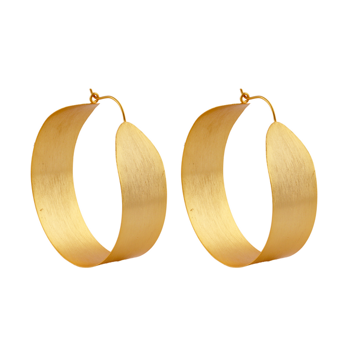 A pair of large, twisted gold hoop earrings with a matte finish, featuring a unique spiral design. The Betty Gold Hoops from Watermelon Tropical have a thin wire hook clasp at the top. These statement hoops are elegantly curved and positioned side by side against a white background.