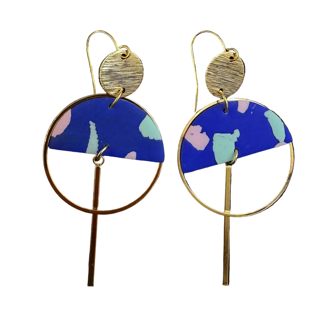 The Sinead Earrings by Kybalion Jewellery feature gold-tone circles and bars, plus blue semicircles with pink, green, and light blue abstract patterns, shown on a black background.