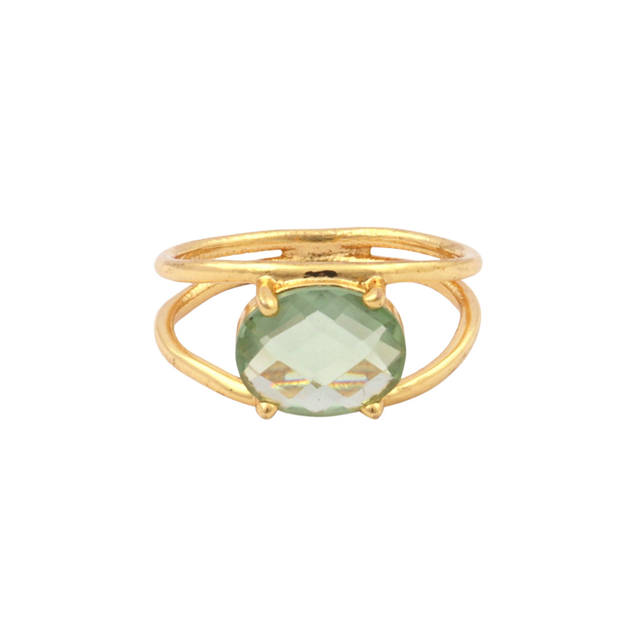 A Charlotte Gold Ring in Green Amethyst by Watermelon Tropical featuring an oval-shaped, faceted green Amethyst at its center. The band splits into two parts, holding the gemstone securely with four prongs. The design is simple yet elegant.