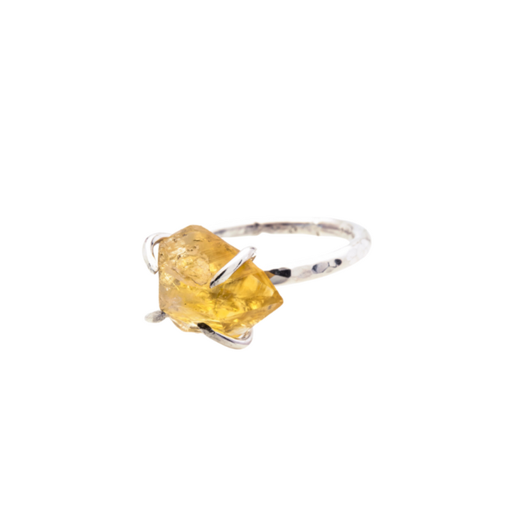 The Caroline Stokesberry-lee Citrine Rock Ring features a raw Citrine gemstone set in an irregular, natural shape. The gemstone is held in place by delicate prongs, showcasing its natural facets. The ring band is slim and polished, highlighting the bright, raw beauty of the stone.
