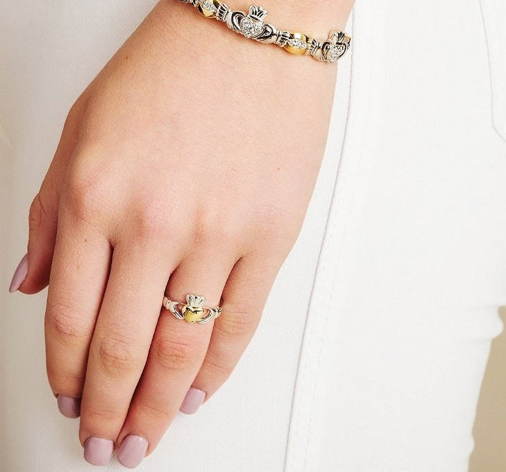 Silver claddagh ring with a gold heart shown on a models hand. 