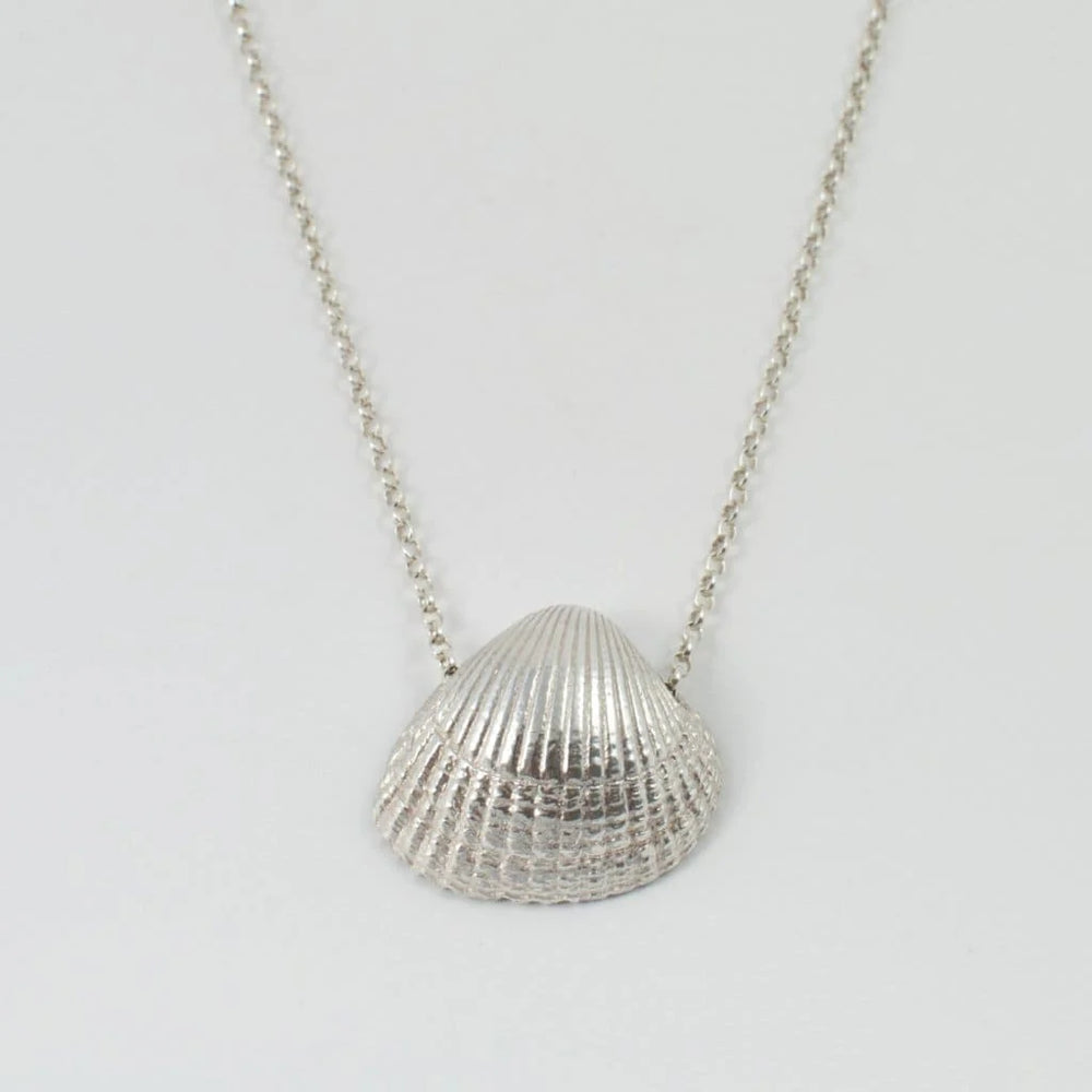 The Jennifer Kinnear Cockle Shell Necklace Small, available in silver or gold, features a detailed, textured cockle shell pendant and is displayed on a light background.
