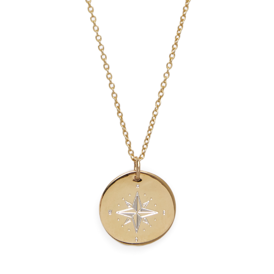 The Symbol Necklace by Personalised Charms is a gold chain with a round engraved compass rose pendant, marked with N, E, S, and W—timeless personalized jewelry adorned with delicate dotted details.