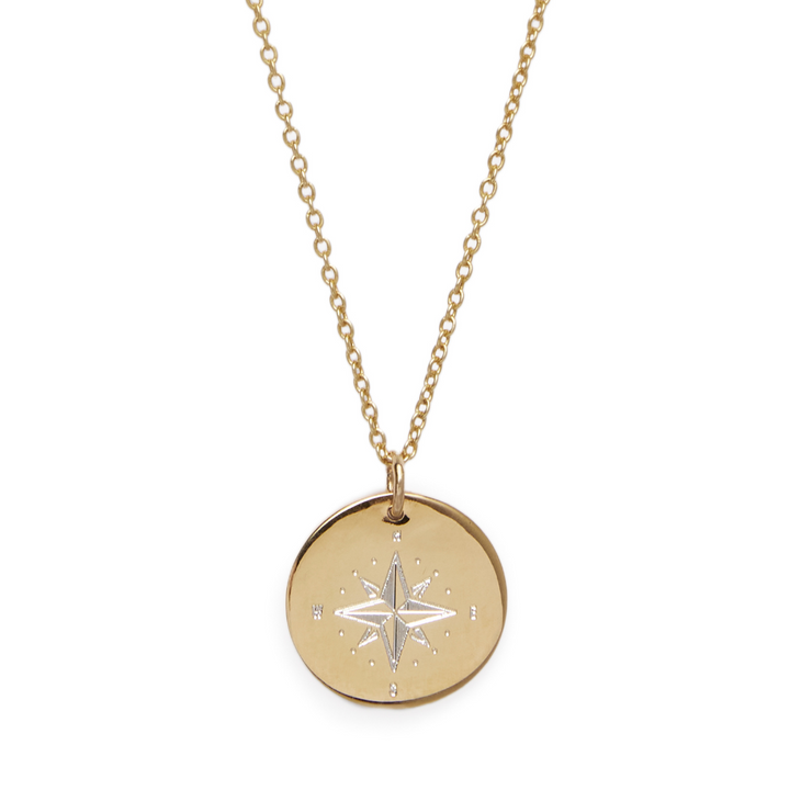 The Symbol Necklace by Personalised Charms is a gold chain with a round engraved compass rose pendant, marked with N, E, S, and W—timeless personalized jewelry adorned with delicate dotted details.