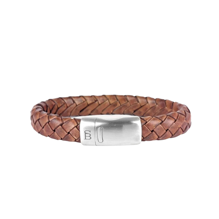 A brown bracelet crafted from genuine braided leather, featuring a silver rectangular stainless steel clasp. The clasp boasts an engraved logo or letter on one side. This accessory combines rustic charm with modern minimalism for a stylish appearance is the Cornall - Caramel by Steel and Barnett.