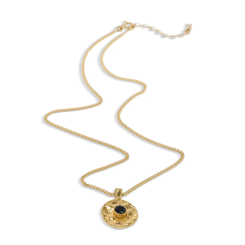 Gold necklace with a circular pendant containing a black stone on a white background