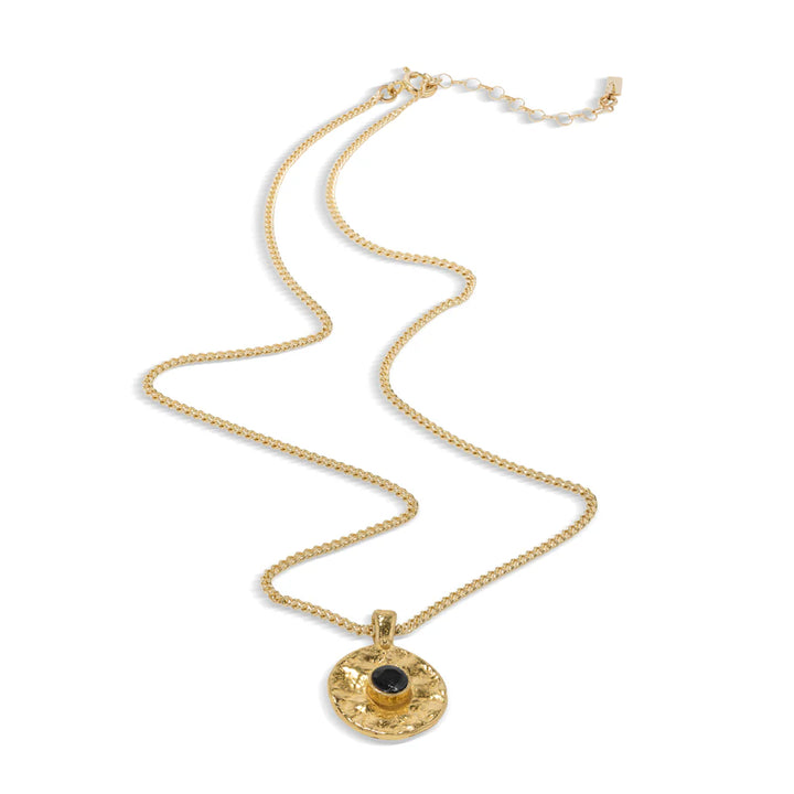 Gold necklace with a circular pendant containing a black stone on a white background