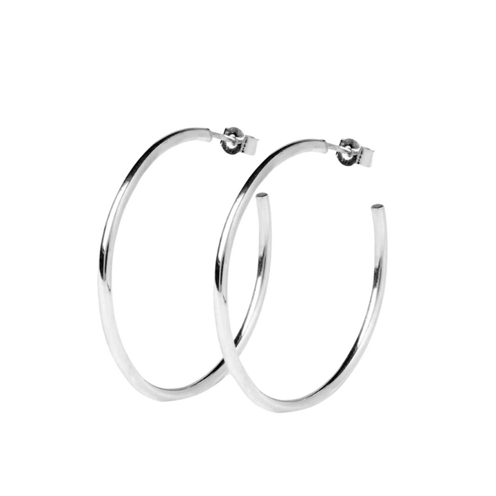 A pair of Cosmic Thread Hoops in shiny silver. The smooth, thin hoops from Cosmic Boulevard feature a simple clasp mechanism for fastening. Set against a plain white background, they highlight the elegance and simplicity of these earrings.