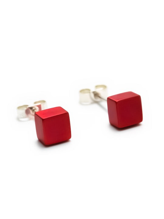 A pair of Small Cube Stud Earrings made from sterling silver, featuring red cube-shaped beads. The earrings have a smooth, minimalist design and are shown on a white background. The product is by Filip Vanas.