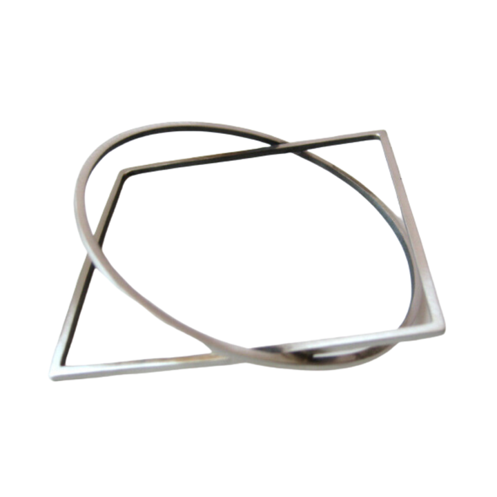 A silver square frame and a silver circular frame are intertwined, creating an abstract geometric shape reminiscent of architectural design. The frames have a sleek and modern look, with clean lines and sharp edges. The background is transparent. Presenting the Cub Silver Bracelet by MarCucurella.