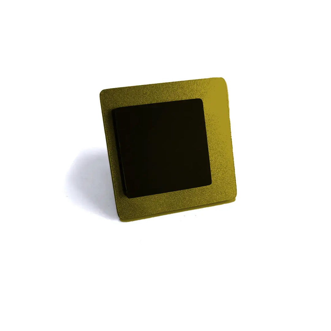 A close-up image of a square electronic chip with a gold-colored outer casing and a black central area, exuding a contemporary touch. The chip is positioned against a plain white background, reminiscent of the precision seen in the Alex + Svet Eriko Ring collection.