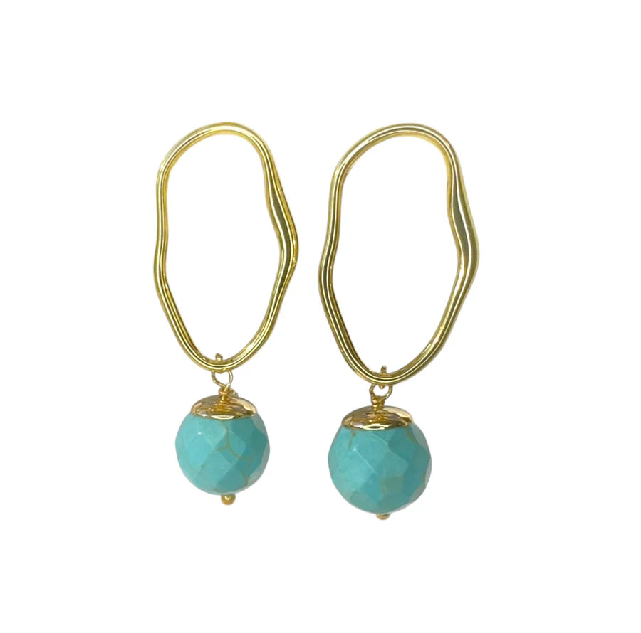 The Eddie Earrings by Aria V are gold plated, handmade in Ireland, and feature irregularly-shaped hoops with faceted turquoise beads dangling at the bottom, shown against a white background.